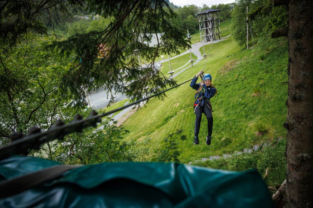 Jente kjører zipline i klatreparken Høyt & Lavt Bergen